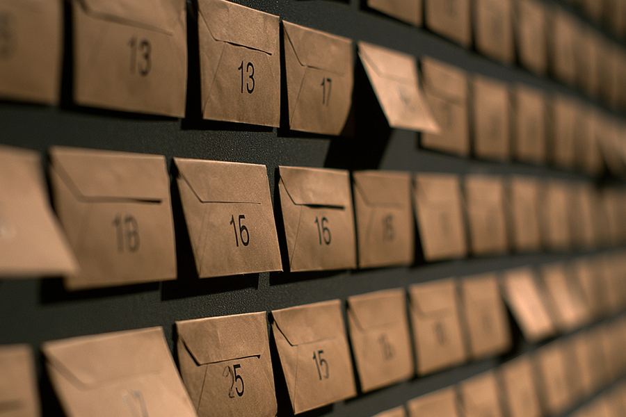 A wall board holding a grid of numbered sealed kraft envelopes